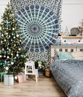 Decorative tapestry with geometric pattern hanging above a bed in a room with a Christmas tree